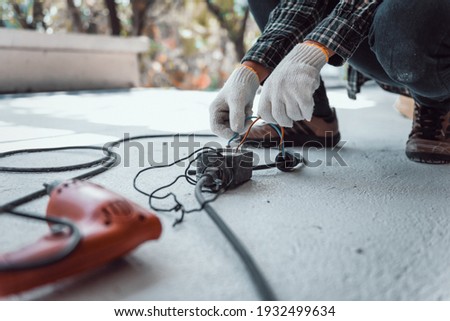 Hand connecting power outlet to an electric tool no electrical plug cause electric shock, Be unaware of worker,  Work accidents electric shock of a worker in the workplace concept.