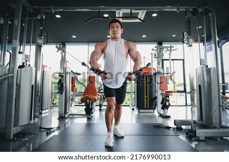 Muscular man, Bodybuilder Asian man work out with cable machine, lifting weights in gym. Fitness execute exercising building muscle with exercise-machine. Stock foto © 