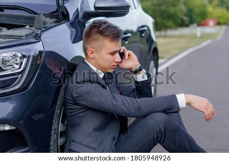 side view of sad businessman use smartphone sitting on road near the broken car opened the hood, calling car assistance services, help repair stress problem emergency insurance aut Stock fotó © 