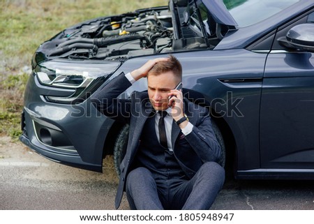sad young man use smartphone sitting on road near the broken car opened the hood, calling car assistance services, help repair stress problem emergency insurance aut. Stock fotó © 