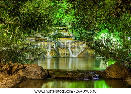 Waterfall with light from lamp in night garden