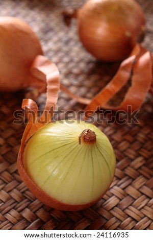 white onion bulb is peeled off rind and on a bamboo tray.