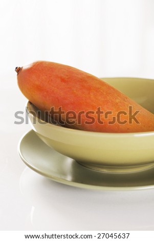 yellow ripe mango in a green bowl.