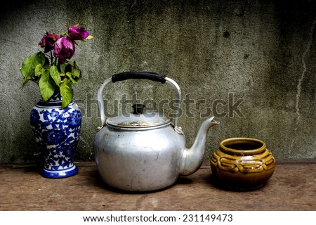 Old silver kettle and vase flower rose  placed on a wooden floor