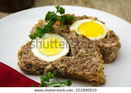 easter meal, meatloaf bread with boiled eggs on a plate, rustic wooden background