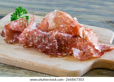 air dried salami in slices on a wooden cutting board