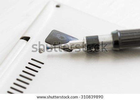 small screwdriver with screw at a technical device, as notebook or laptop, precision work or hardware upgrade, macro, selected focus, shallow depth of field, almost silver and black, Copy Space