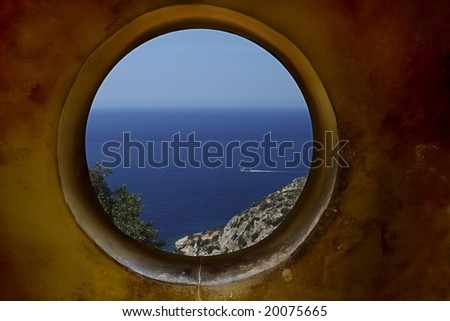 A rustic round window in a shabby wall with brush marks and a sea view; clipping path included
