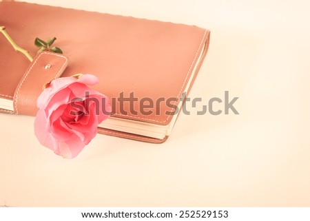 Pink rose on old leather book in vintage style