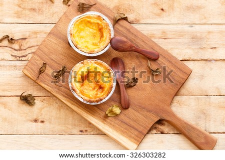 Egg tarts and wooden spoons on wooden plate.Dessert food menu.