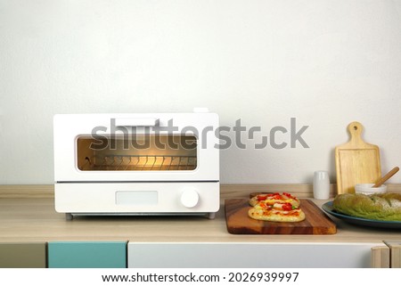 white modern design toaster oven is on the wooden table with pizza and homemade bread toast white cement wall background in minimal design kitchen
