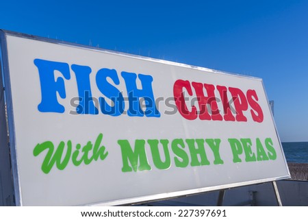 Advertising sign for fish and chips with mushy peas on the beach front