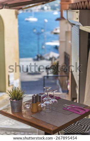 A bistro table outside a brasserie with a view of the harbour in the distance