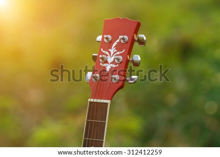 blurry and soft focus of guitar on grass at sunset