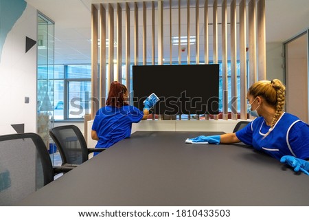 Two cleaners with masks on their faces are cleaning the office photo