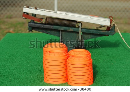 Clay pigeons stacked next to a portable trap thrower mounted on a table at a trap and skeet club