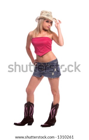 Beautiful young cowgirl with blond hair in a short denim skirt, pink top, pink and brown suede boots and a cowboy hat