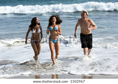 A man and two young women running from the surf at the beach