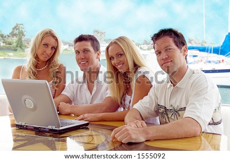 Two young couples on a private yacht in the harbor closing a business deal on a laptop computer