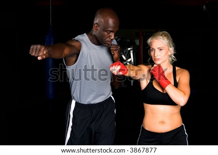 Beautiful but dangerous woman fighter working on her right cross with her trainer in an Mixed Martial Arts gym.