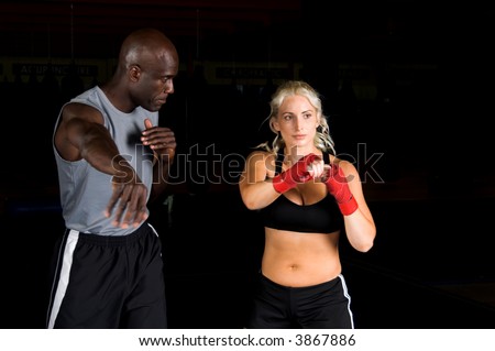 Beautiful but dangerous woman fighter practicing her right cross with her trainer in an Mixed Martial Arts gym.