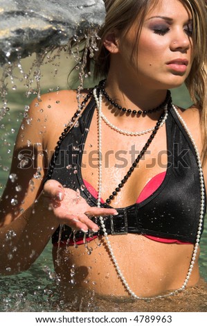 Sexy Caucasian woman wearing a black and pink bikini and in a small waterfall