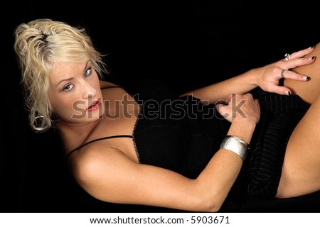 Pretty blonde fashion model with short blond hair laying on a black  couch