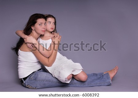 A mother hugs her young daughter in a formal portrait
