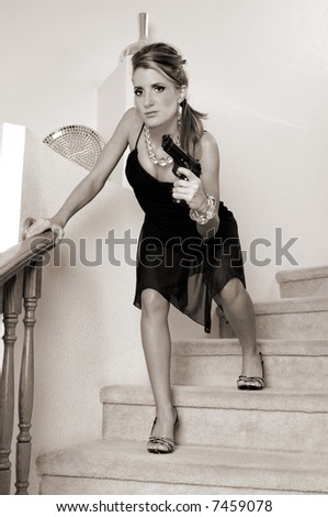 Young woman in a black cocktail dress and crystal necklace and bracelet sneaking down the stairs with a 45 caliber handgun