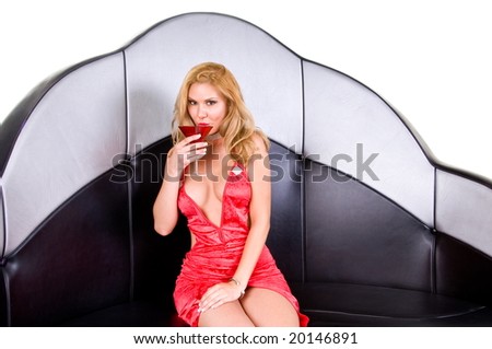Blond fashion model wearing a low cut  vintage style red dress cut high up the front sitting on a vintage lounge booth