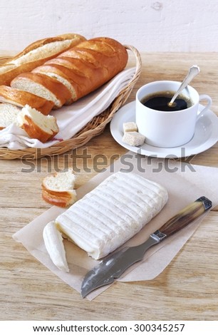 Breakfast: goat cheese, baguette in wicker basket and cup of coffee