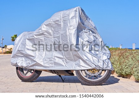 Similar – Image, Stock Photo Waterproof cover for motorcycle with silver reflective protective surface. Motorcycle covered with fabric shield and parked outside