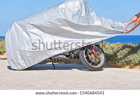 Similar – Image, Stock Photo Waterproof cover for motorcycle with silver reflective protective surface. Motorcycle covered with fabric shield and parked outside