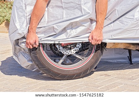 Similar – Image, Stock Photo Waterproof cover for motorcycle with silver reflective protective surface. Motorcycle covered with fabric shield and parked outside