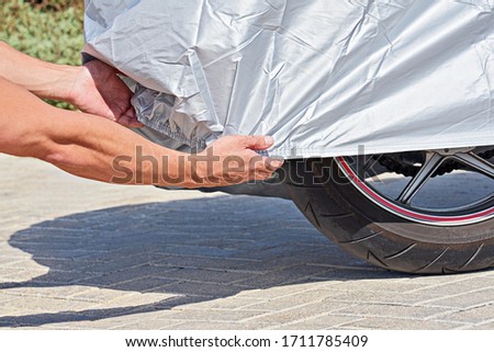 Similar – Image, Stock Photo Waterproof cover for motorcycle with silver reflective protective surface. Motorcycle covered with fabric shield and parked outside