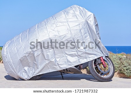 Similar – Image, Stock Photo Waterproof cover for motorcycle with silver reflective protective surface. Motorcycle covered with fabric shield and parked outside