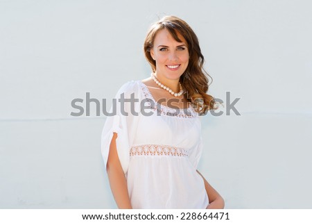 Long haired smiling young woman looking at camera, wearing white tunic