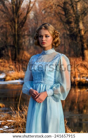 Portrait of romantic woman in vintage dress on the river bank