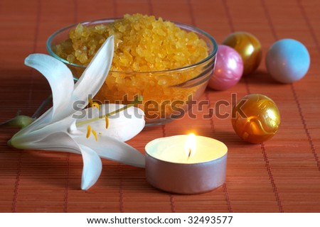 Bath salt and white lily on bamboo mat in light of aroma candle