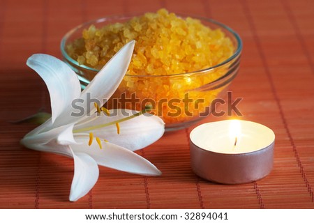 Bath salt and white lily on bamboo mat in light of aroma candle