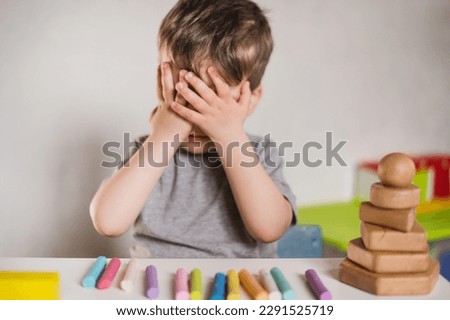 Similar – Image, Stock Photo Boy with Autism communicating with ipad while eating a homemade gluten free muffin; plastic animal toys nearby