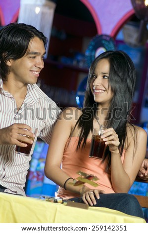 A young couple enjoys a drink in a local Mexican restaurant type of place.