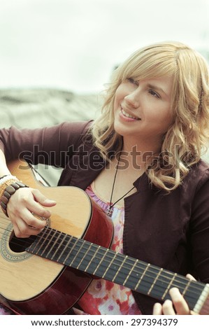 A young woman playing the guitar on a grunge rooftop.