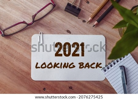 2021 looking back text on white card on office desk. Year highlights concept. Top view. 