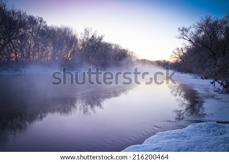 Winter landscape with foggy river at sunrise. Very cold weather.