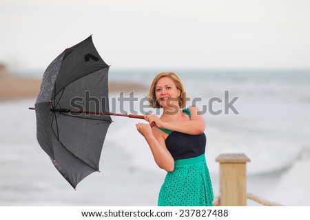 Beautiful girl with umbrella in the rain on the beach.