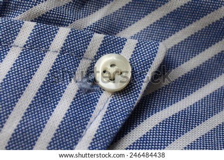 Fragment of shirt. Fabric in blue and white stripes with a button.