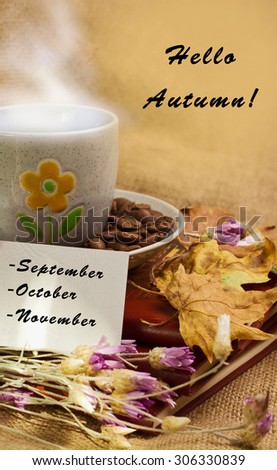 Banner with words hello autumn and the cup of coffee lying on the books with dry yellow maple leaves and everlasting flowers on sackcloth background