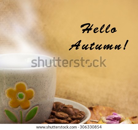 Banner with words hello autumn and the cup of coffee lying on the books with dry yellow maple leaves and everlasting flowers on sackcloth background
