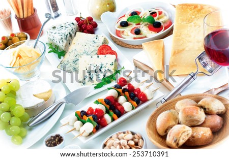 Cheese and snack buffet arrangement with various cheeses, wine, dressings, bread and snack food